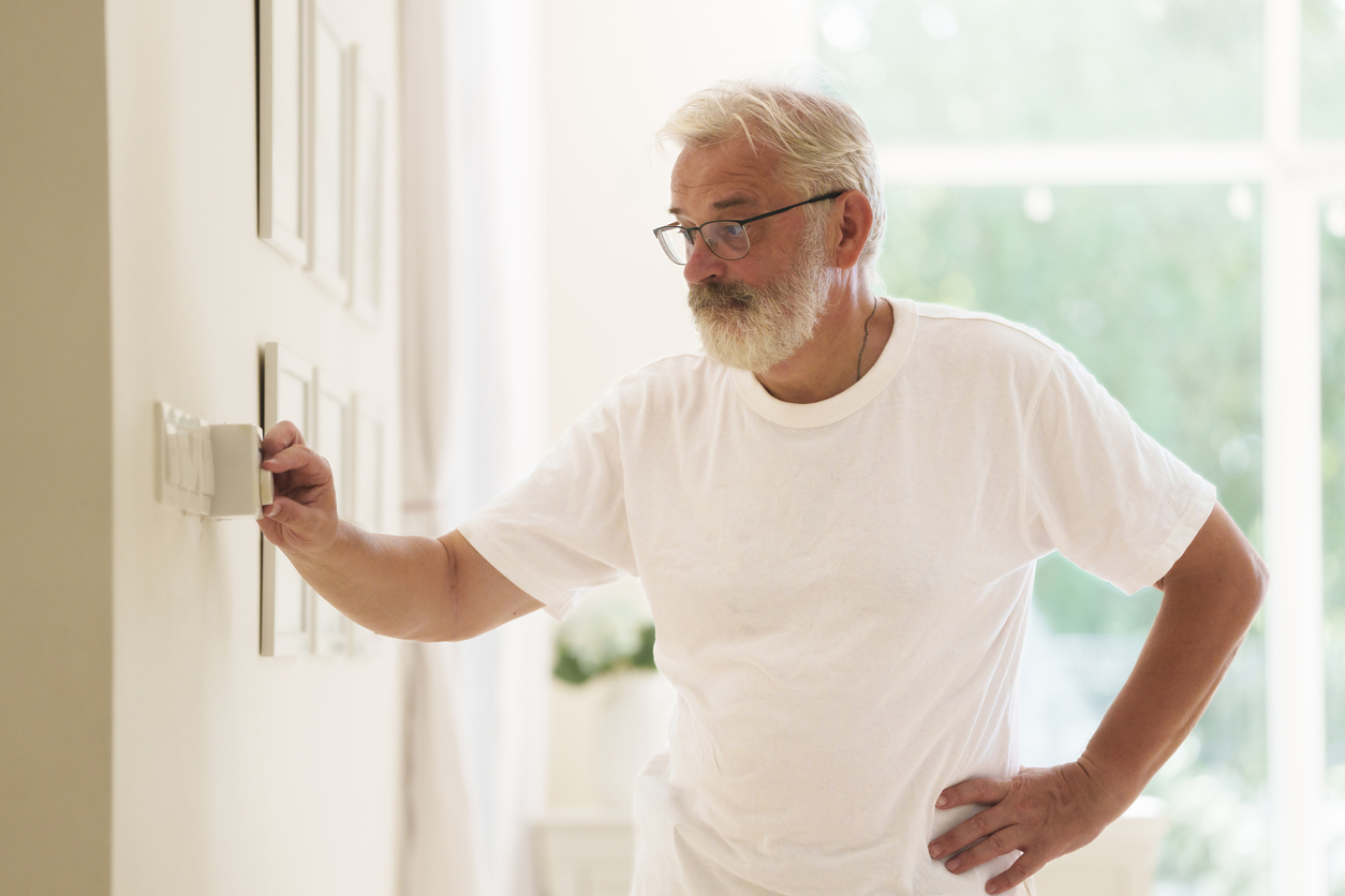 Man adjusts a thermostat that is not working right and needs to be replaced